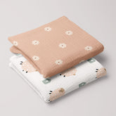 Folded baby swaddles with salmon floral and sheep print on organic muslin